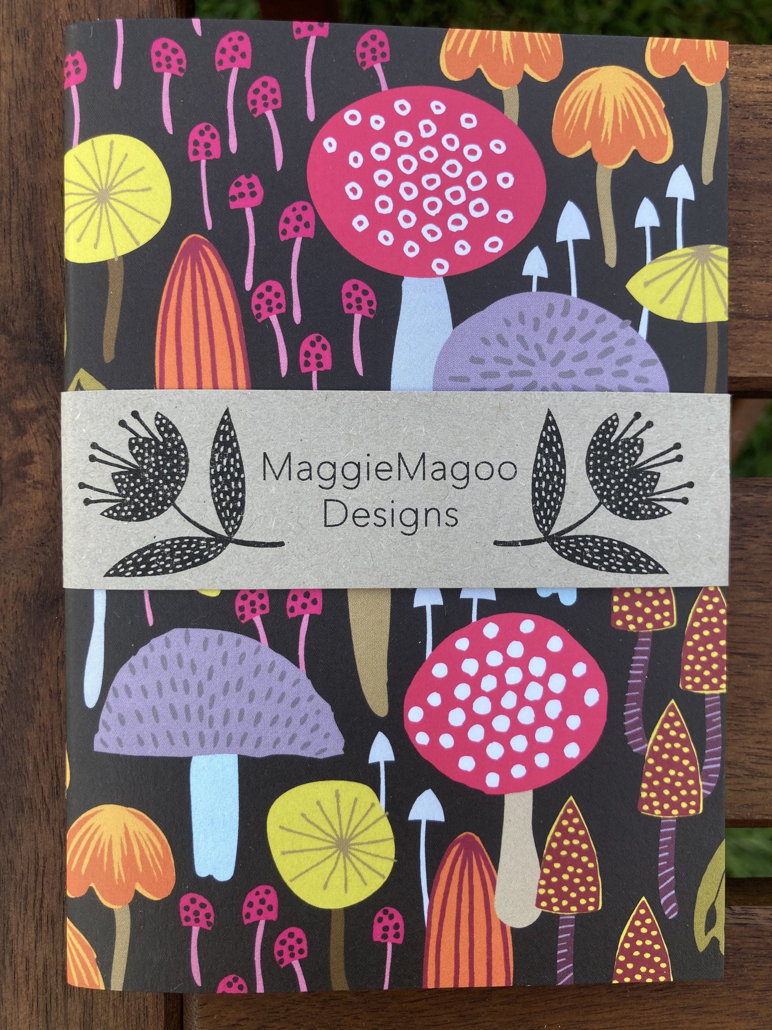 Black background with mushrooms in all shapes and sizes.  Some thin and tiny and some big and round.  Bright colors of pink, orange, yellow and lavender are off set with internal patterns of dots, circles and stripes.  